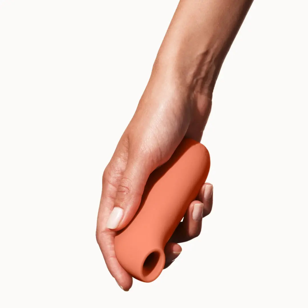 Dame Aer clitoral suction toy in papaya orange held in hand